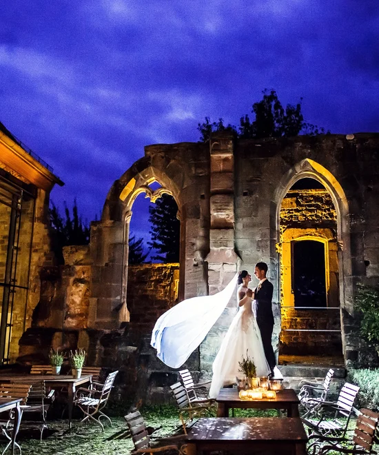 The right offer for every occasion Bride and groom at night in front of lit historic ruins and tables