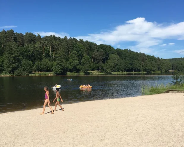 Ausflugstipps für Ihren Urlaub in der Pfalz Kinder laufen am Sandstrand eines Sees mit Menschen auf Booten im Wasser