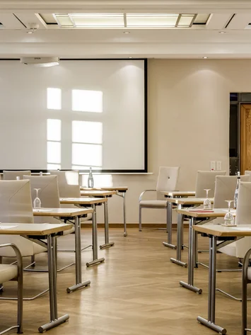 Tagungsräume Pfalz | Historische & moderne Räume im Kloster Hornbach Heller Konferenzraum mit weißen Stühlen, Tischen und Projektionsleinwand