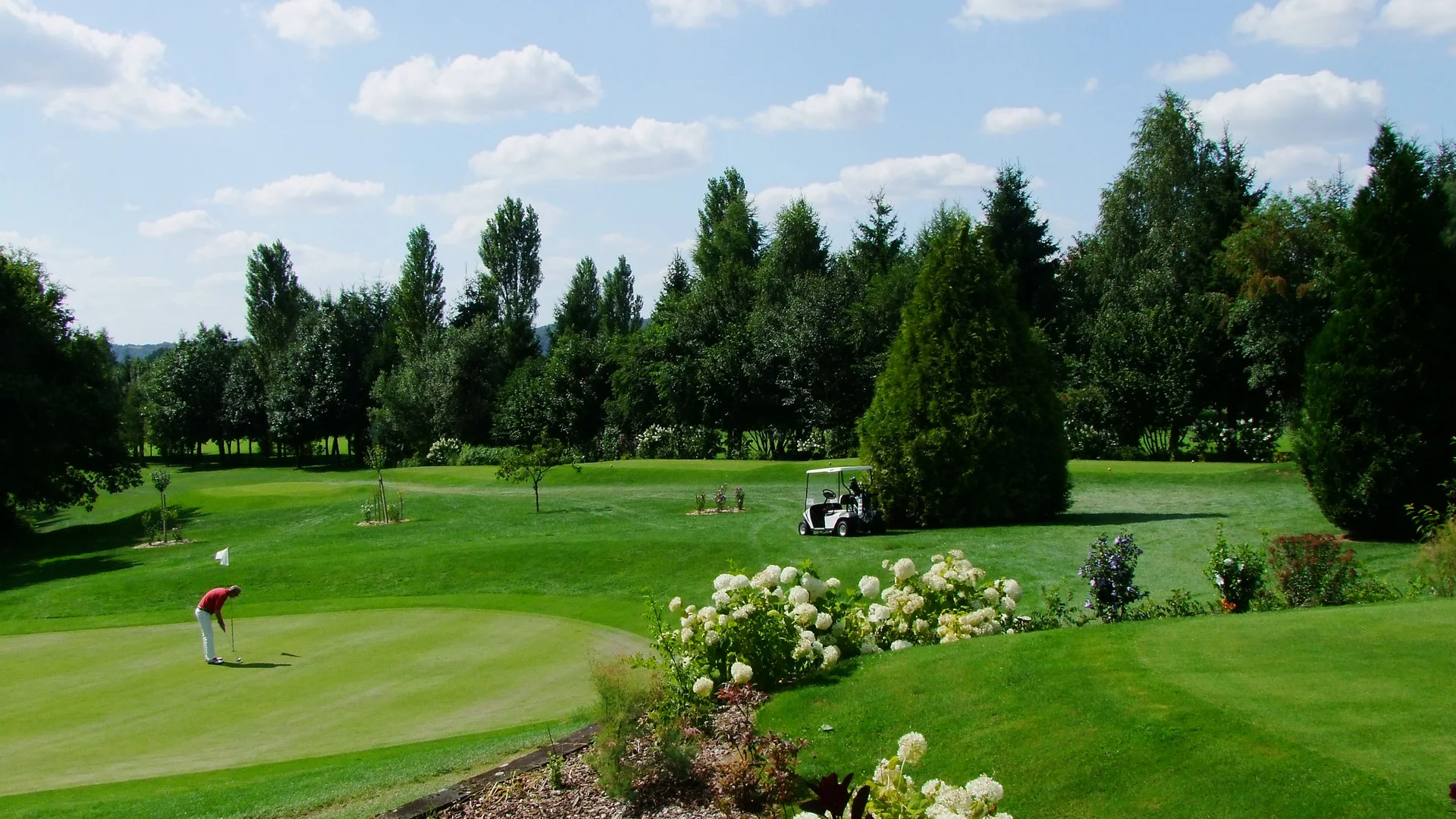 Golfen im Saarland, in Frankreich und in der Pfalz Golfplatz mit Golfer, Bollerwagen und blühendem Garten bei sonnigem Wetter