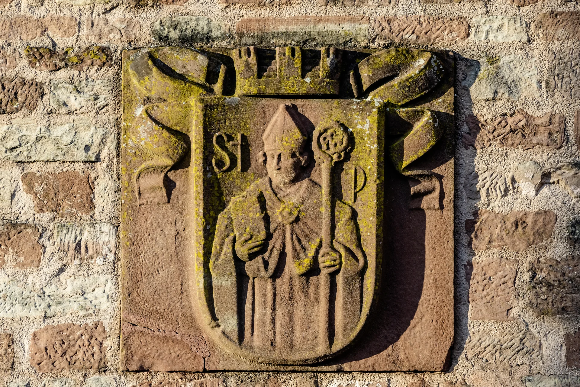 Ihre Gastgeber im Kloster Hornbach Steinrelief eines Bischofs mit Mitra und Stab an einer Steinmauer