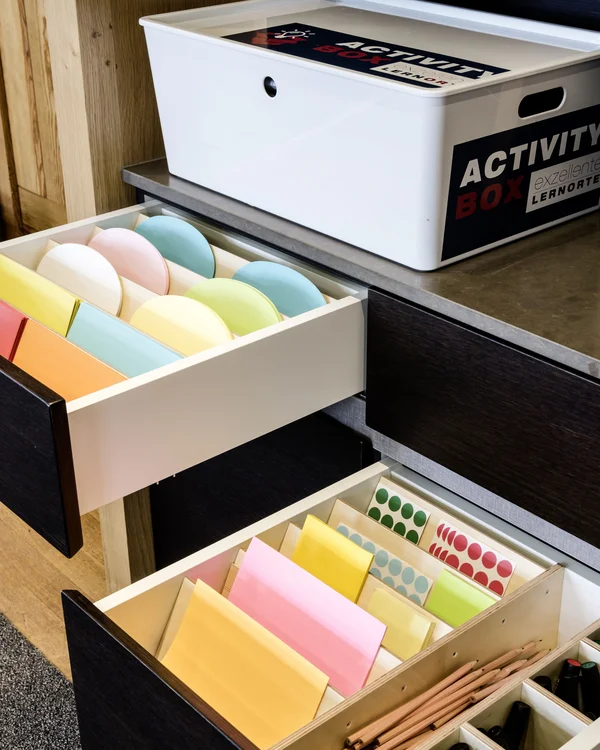 Exzellenter Lernort Kloster Hornbach Offene Schubladen mit buntem Papier und Stiften neben einer weißen Activity Box