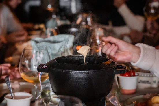 ABBA-Dinner – A Night to Remember Menschen essen gemeinsam Fondue an festlich gedecktem Tisch