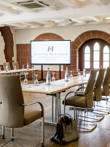 Tagungsräume Pfalz | Historische & moderne Räume im Kloster Hornbach Moderner Konferenzraum mit Bildschirm und bestuhltem Tisch in Kloster Hornbach