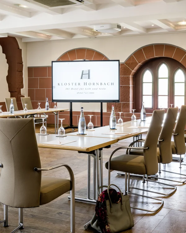 Ihr Tagungshotel Pfalz | Kreative Meetings im historischen Kloster Hornbach Moderner Konferenzraum mit Bildschirm und bestuhltem Tisch in Kloster Hornbach