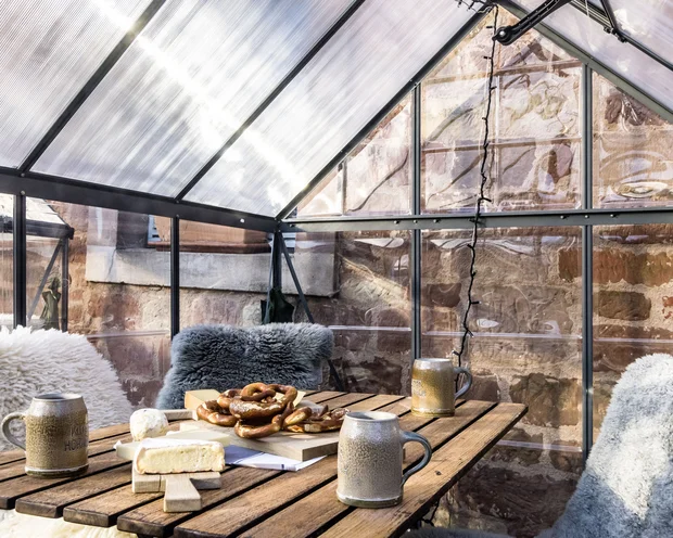 Treffpunkt, Kraftplatz und Hotel in Hornbach Gemütlicher Tisch im Gewächshaus mit Brezeln, Käse und Bierkrügen