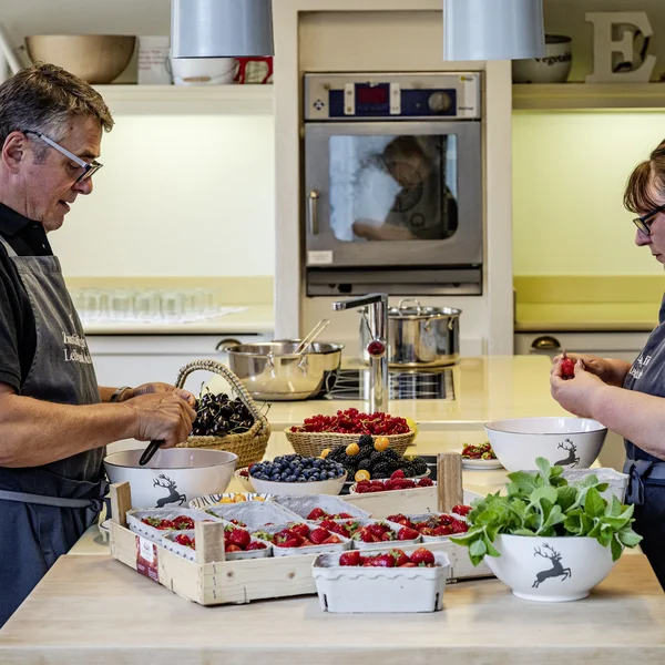 Treffpunkt, Kraftplatz und Hotel in Hornbach Zwei Personen bereiten frische Beeren in einer Küche mit weißen Schüsseln und Holztabletts vor