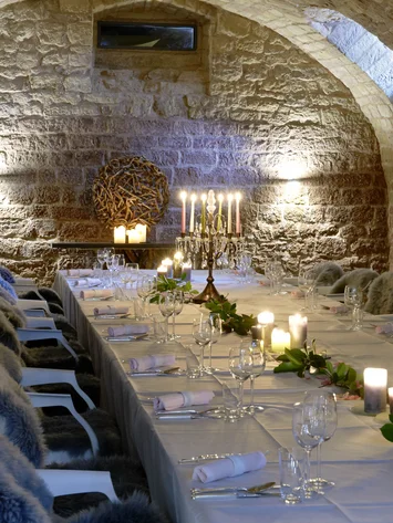 Our venue, your dream wedding Elegant table in a stone vaulted cellar with candles and fur-covered chairs